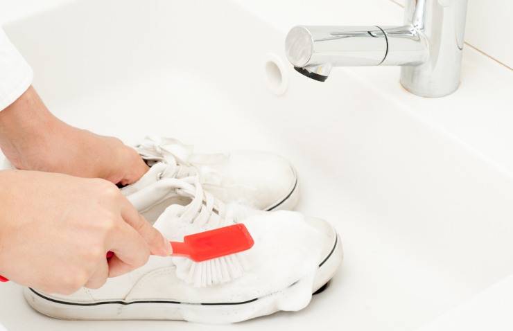 mani lavano scarpe nel lavandino con spazzola