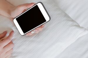smartphone in mano sopra a un letto
