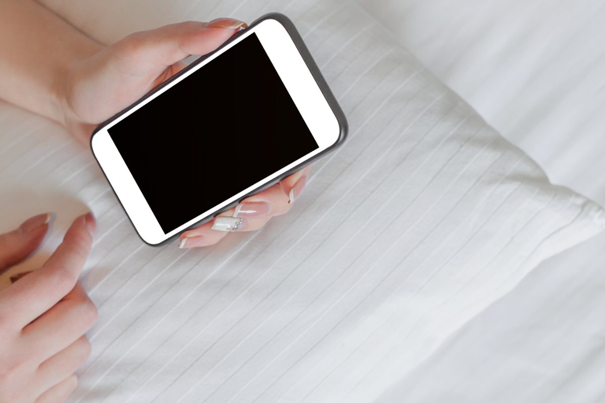 smartphone in mano sopra a un letto