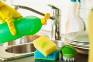 Donna che versa sapone per i piatti sulla spugna