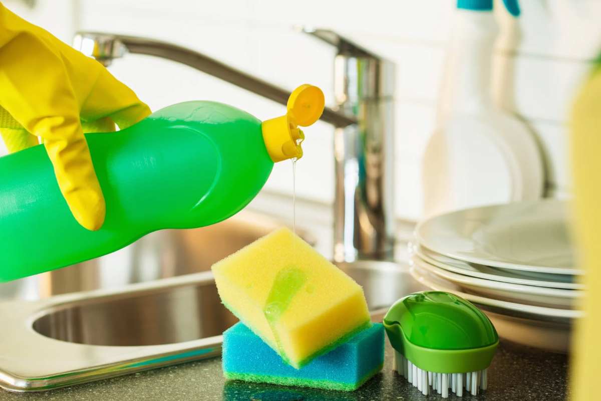 Donna che versa sapone per i piatti sulla spugna