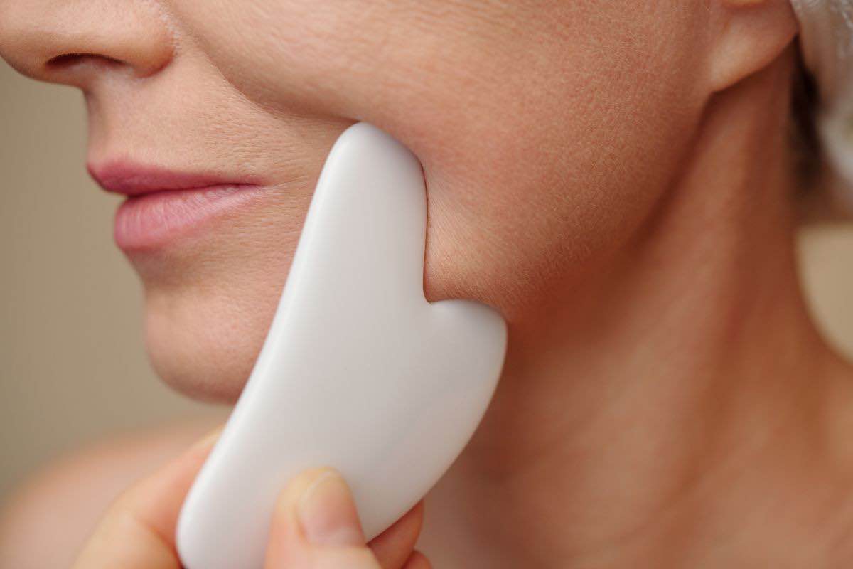 Donna che preme gua sha sul viso