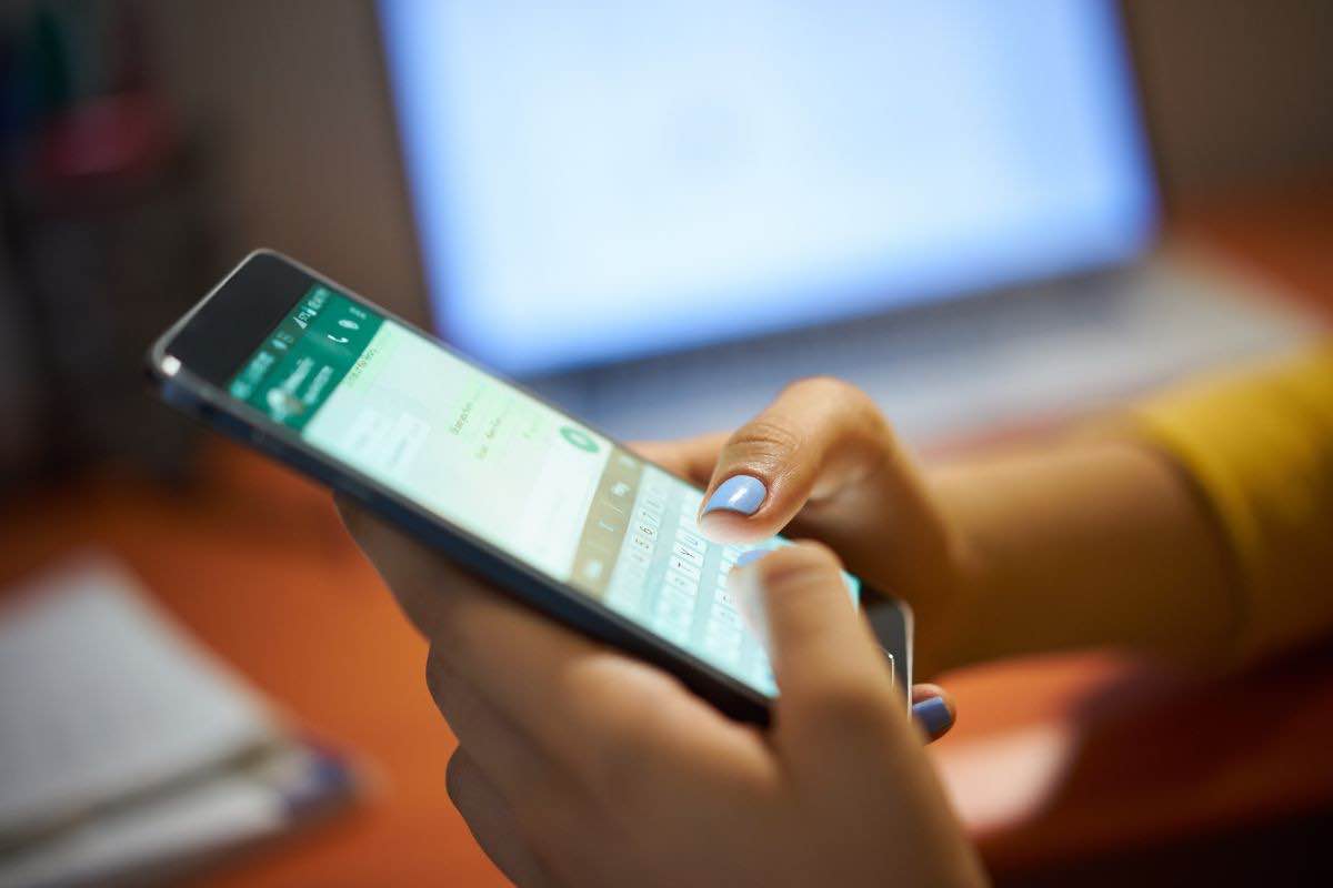 Persona con cellulare in mano e chat Whatsapp