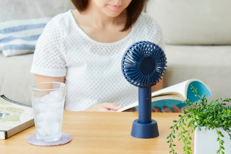 donna che legge con ventilatore e bicchiere di ghiaccio