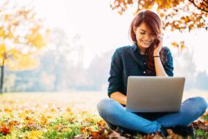 ragazza in mezzo ad un prato con il computer sulle ginocchia