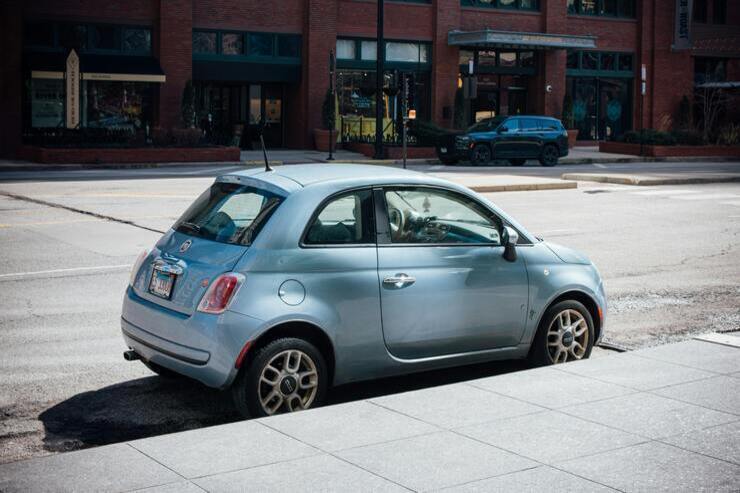 Fiat 500 azzurra parcheggiata accanto al marciapiede