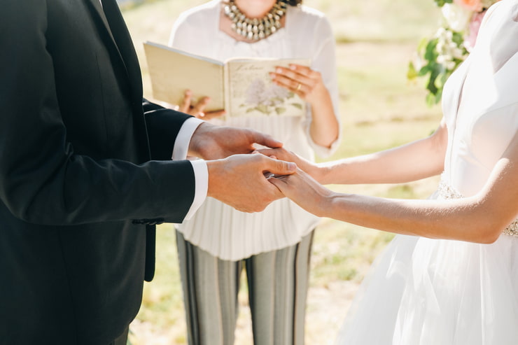 Sposi che si tengono per mano davanti all'officiante