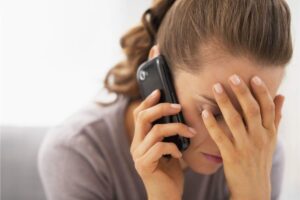 Donna mano sul viso, al telefono, preoccupata