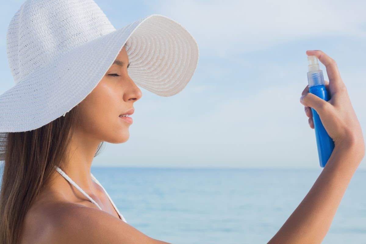 Donna che applica crema solare spray