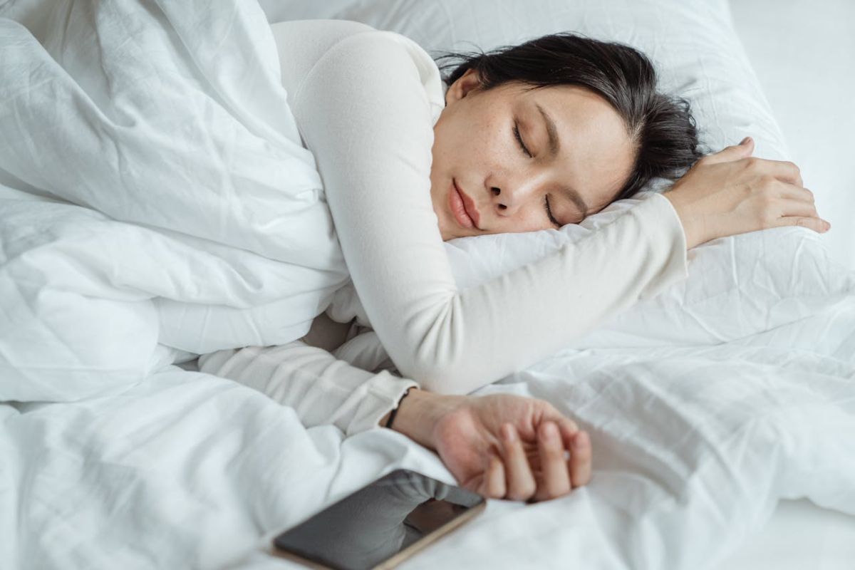 Ragazza che dorme con lo smartphone vicino