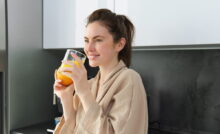ragazza che sorride e beve un bicchiere di succo