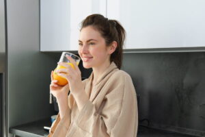 ragazza che sorride e beve un bicchiere di succo