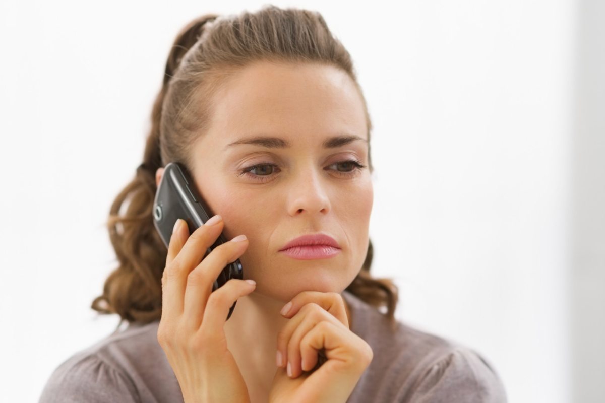 Donna con il telefono all'orecchio ed espressione seria