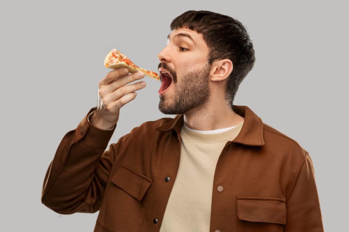 Uomo che sta per mangiare una fetta di pizza
