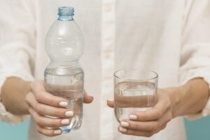 Donna che tiene in mano una bottiglia d'acqua e un bicchiere