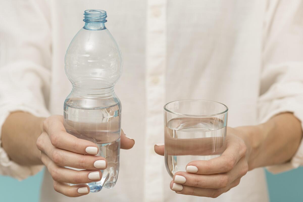 Donna che tiene in mano una bottiglia d'acqua e un bicchiere