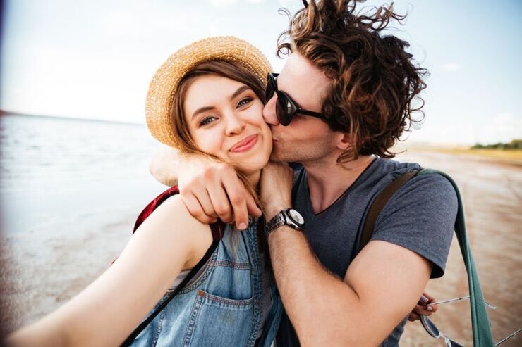 Coppia lui dà un bacio sulla guancia a lei che è sorridente 
