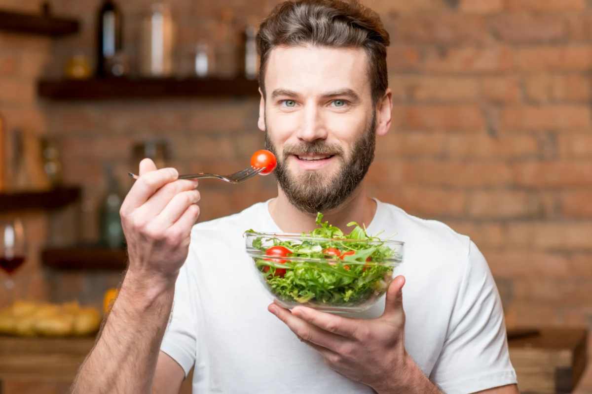 Uomo che mangia insalata con pomodorini