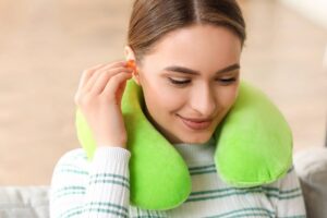 Donna con cuscino per il collo e tappi per le orecchie