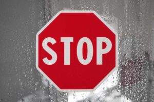 acqua su parete in vetro e scrita stop in rosso al centro