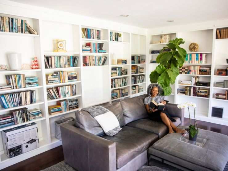 donna seduta su un grande divano in un soggiorno con una libreria