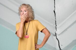 donna spaventata da una crepa nel muro